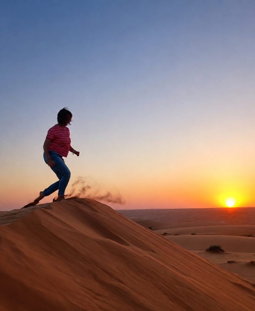 Femme marchant sur une dune de sable au coucher de soleil, symbole de mouvement et de transformation